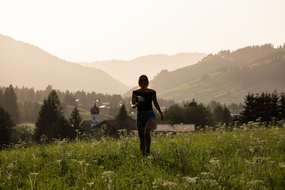 Frau auf Blumenwiese im Sonnenuntergang
