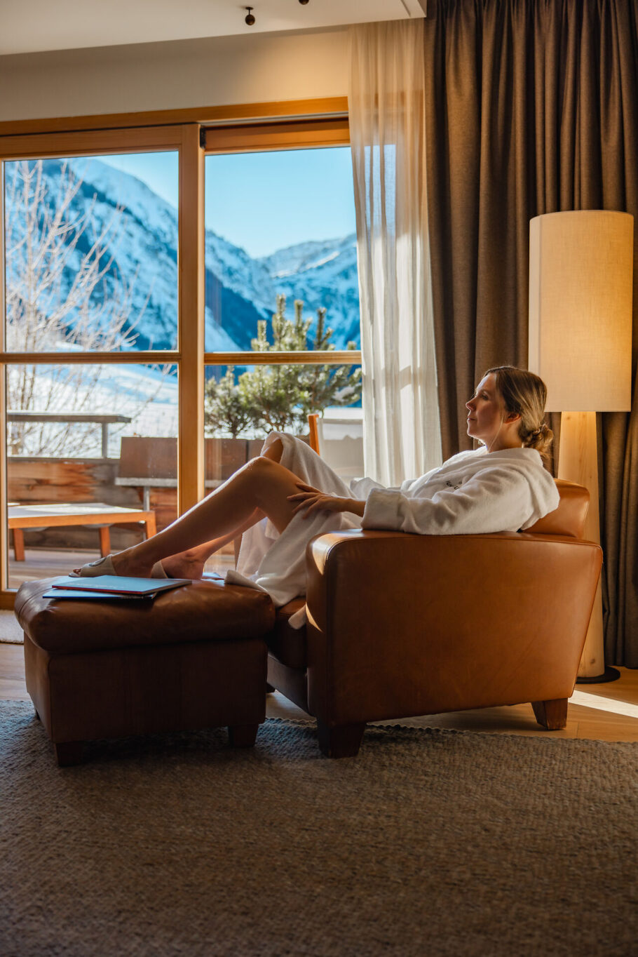 Frau in der Suite Bergfeuer beim Lesen mit Ausblick in die Berge des Tannheimer Tals